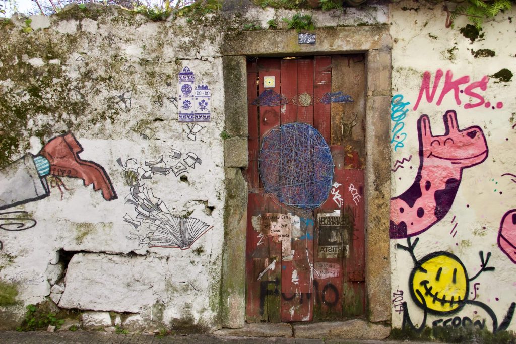 An old door surrounded by funky street art and azulejos tiles in Porto, Portugal. ©KettiWilhelm2020