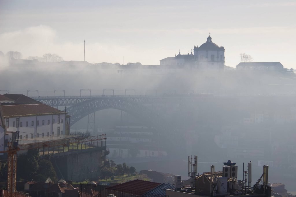 Morning fog hanging over the Douro River, with the Dom Luis Bridge and a castle visible in the background. ©KettiWilhelm2020