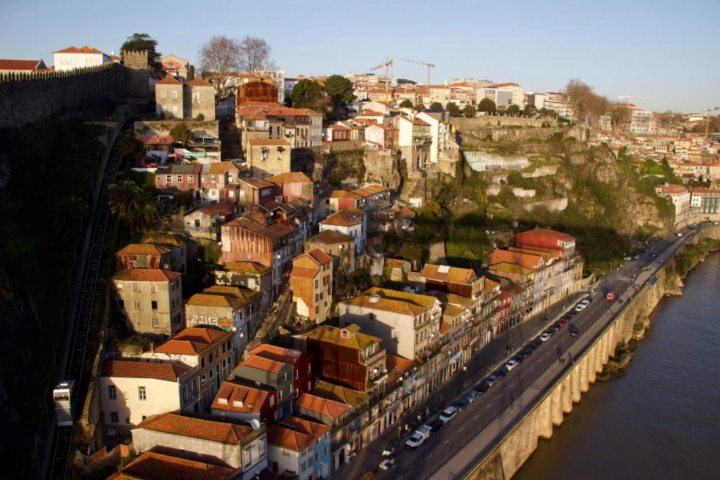 Views from a layover in Porto: A hill covered in houses next to the Douro River, bathed in the light of a sunset. ©KettiWilhelm2020