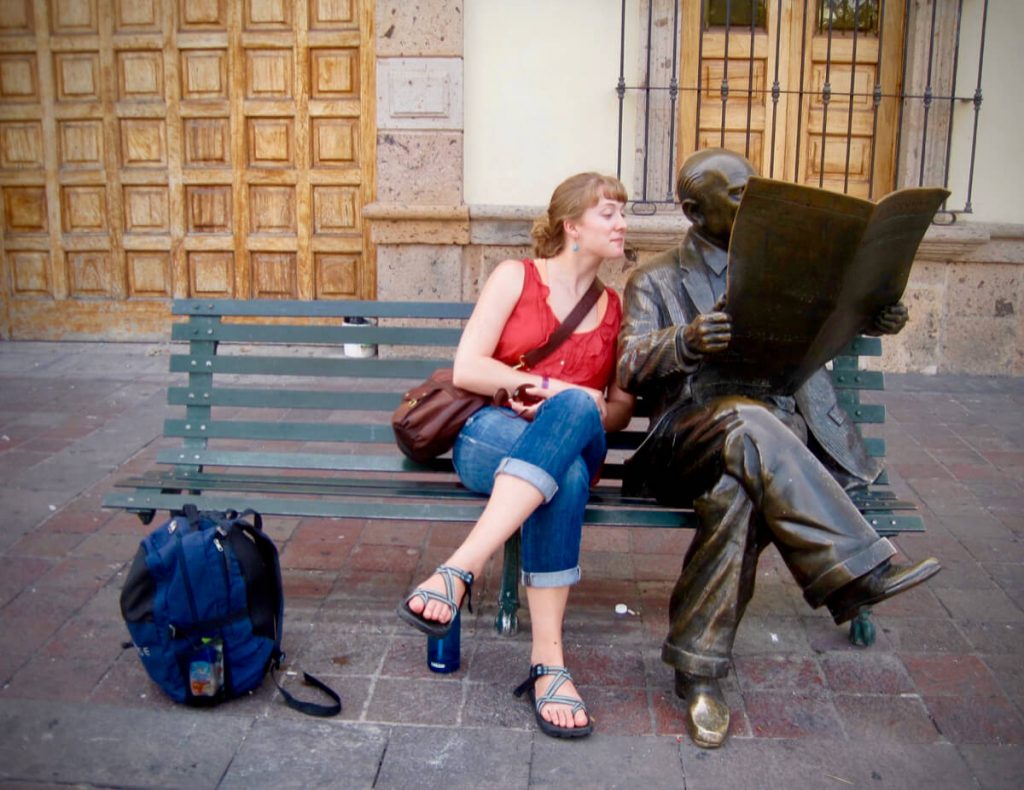 Ketti Wilhelm in Guadalajara, Mexico, sitting next to to a statue of a journalist reading a newspaper. ©KettiWilhelm2013