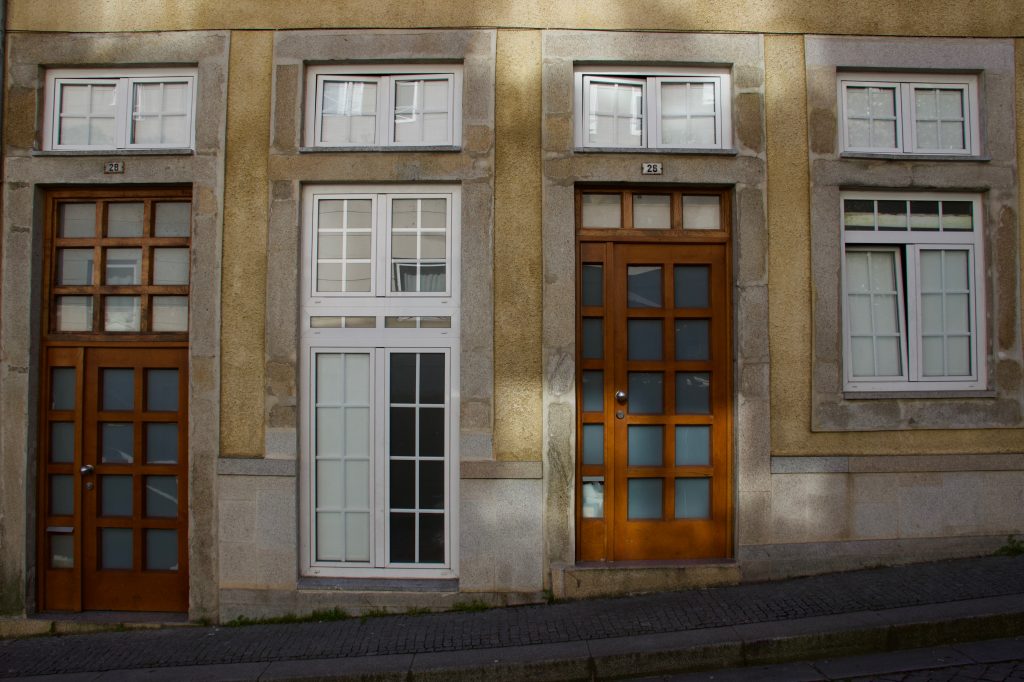 A line of uniform wooden doors and white windows on a street in Porto, Portugal. ©KettiWilhelm2020