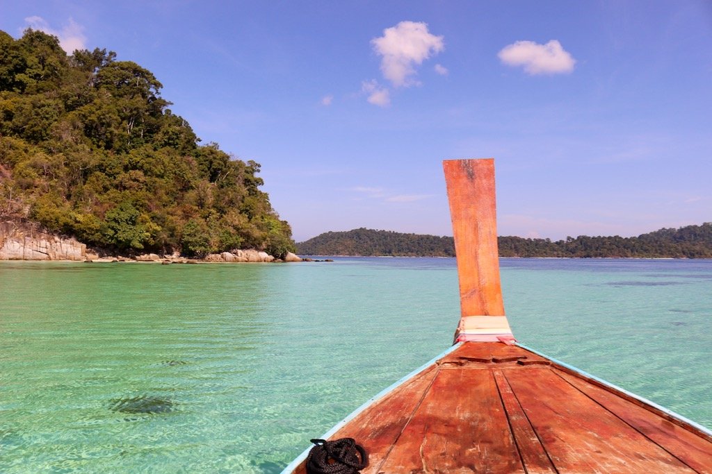 The view of steep cliffs and turquoise waters from the front of a long tail boat in Thailand. ©KettiWilhelm2019