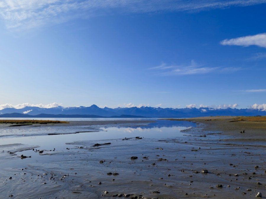 A beach near Juneau, Alaska, covered with a thin layer of water reflecting the mountains behind it on a bluebird day. ©KettiWilhelm2020