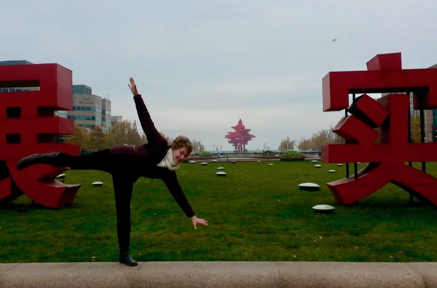 The author, Ketti Wilhelm, doing a cartwheel in front of giant statues of Chinese characters, in Qingdao, China. ©KettiWilhelm2014