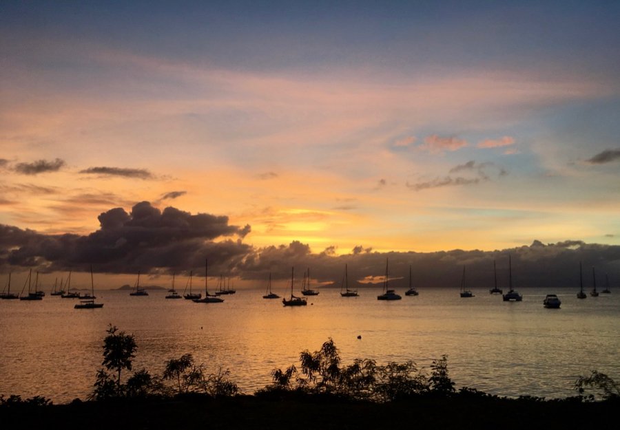 A blue and gold sunset over Caribbean Sea – filled with sailboats – in Guadeloupe. Taken at the end of long work day an international travel guide. ©KettiWilhelm2020