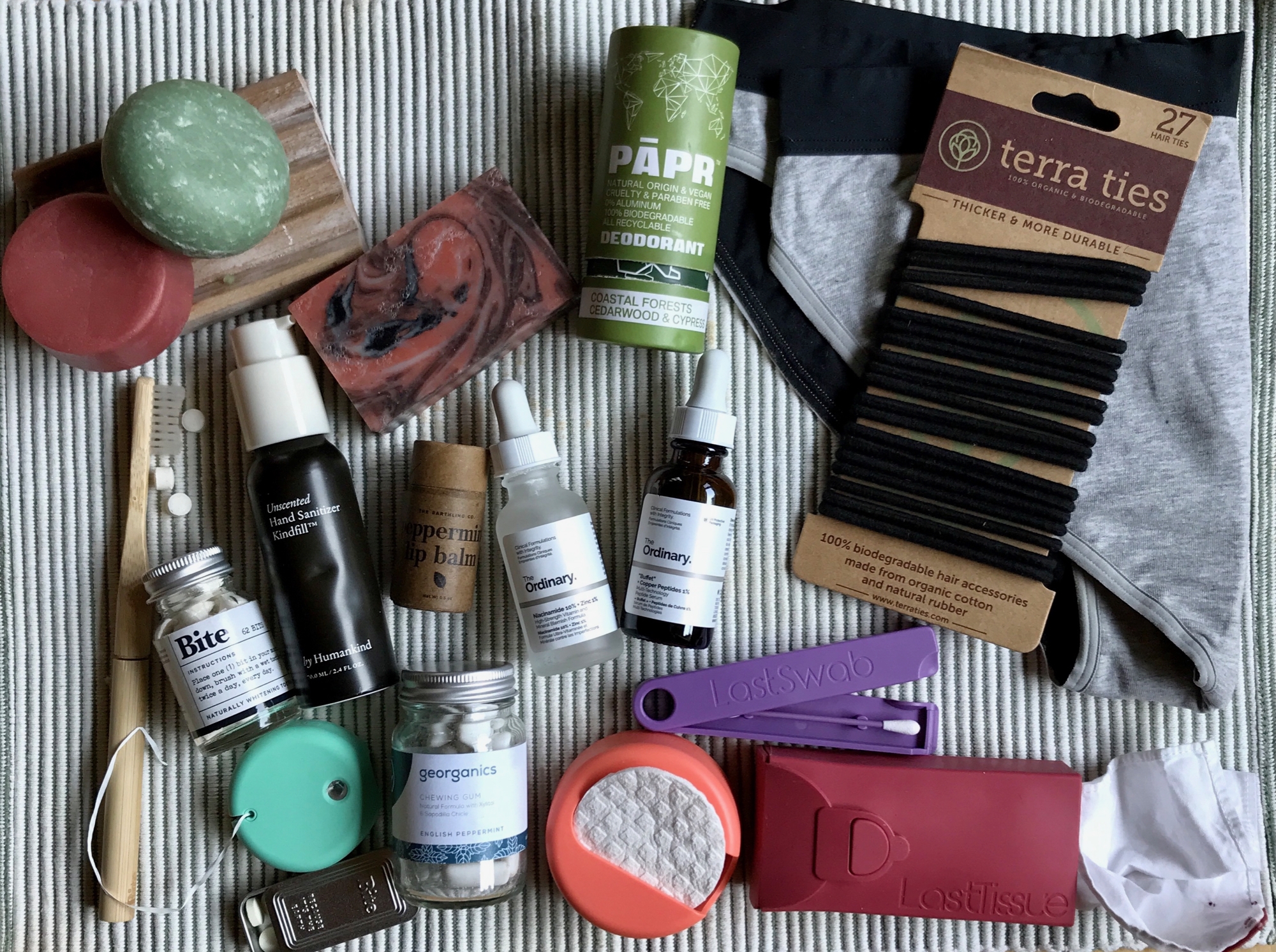 My zero-waste toiletry routine (including glass bottled products from DECIEM, a brand that has a TerraCycle recycling program, and many plastic-free options) sitting on a light green cloth. ©KettiWilhelm2021