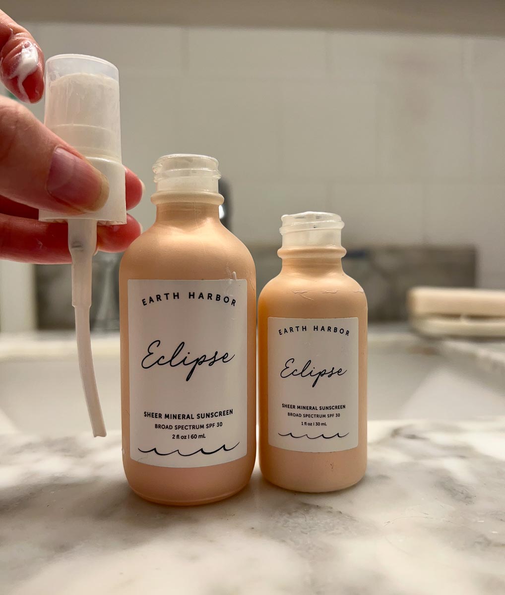 Earth Harbor's new refillable glass bottles for skincare, with reusable pumps – a larger refill bottle next to a small bottle, showing that the pump tube is not long enough to use on the larger bottle. ©KettiWilhelm2022