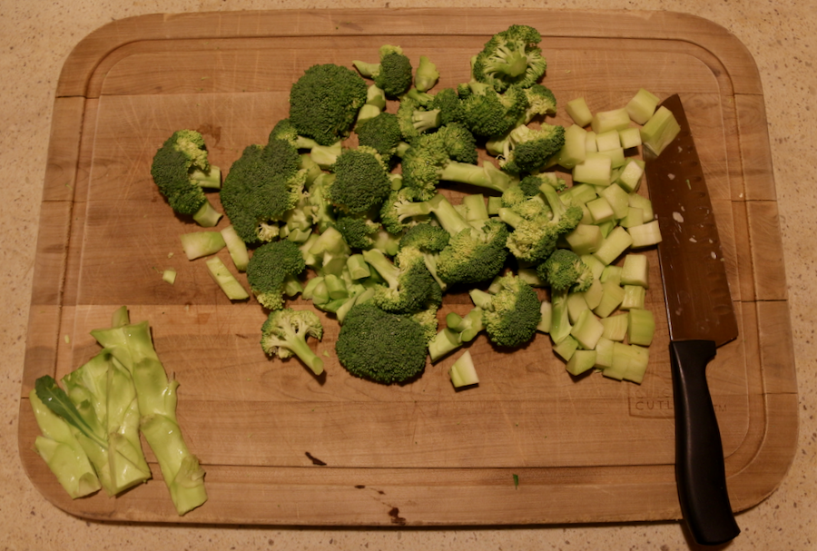 Chopped broccoli, including the peeled stems, on a wooden cutting board, prepped for to be boiled for Pasta with Broccoli. ©KettiWilhelm2021