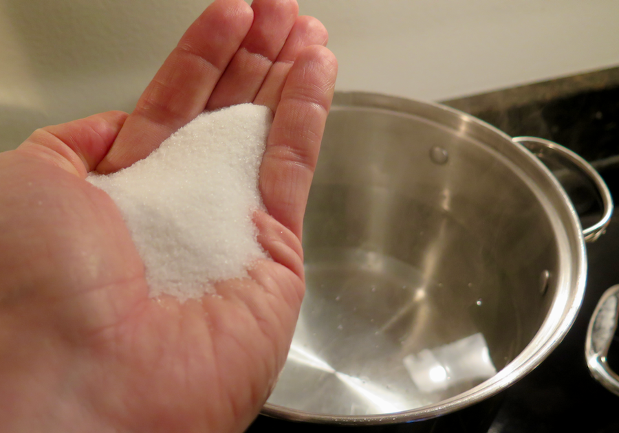 A handful of salt ready to be dumped in the pasta water (in a pot in the background) for this Italian recipe. ©KettiWilhelm2021