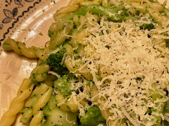 A very close-up shot of a plate of fusilli pasta with broccoli, topped with Parmigiano Reggiano cheese. An authentic Italian recipe. © KettiWilhelm2021