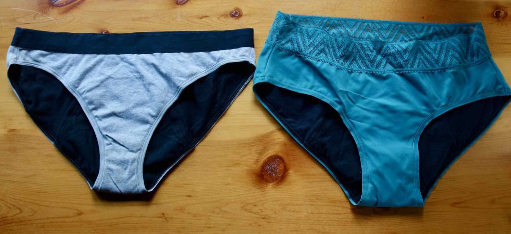 Two similar styles of Thinx period underwear on a wooden table: The Organic cotton bikini on the left in gray, and the Hiphugger style on the right in turquoise. ©KettiWilhelm2021