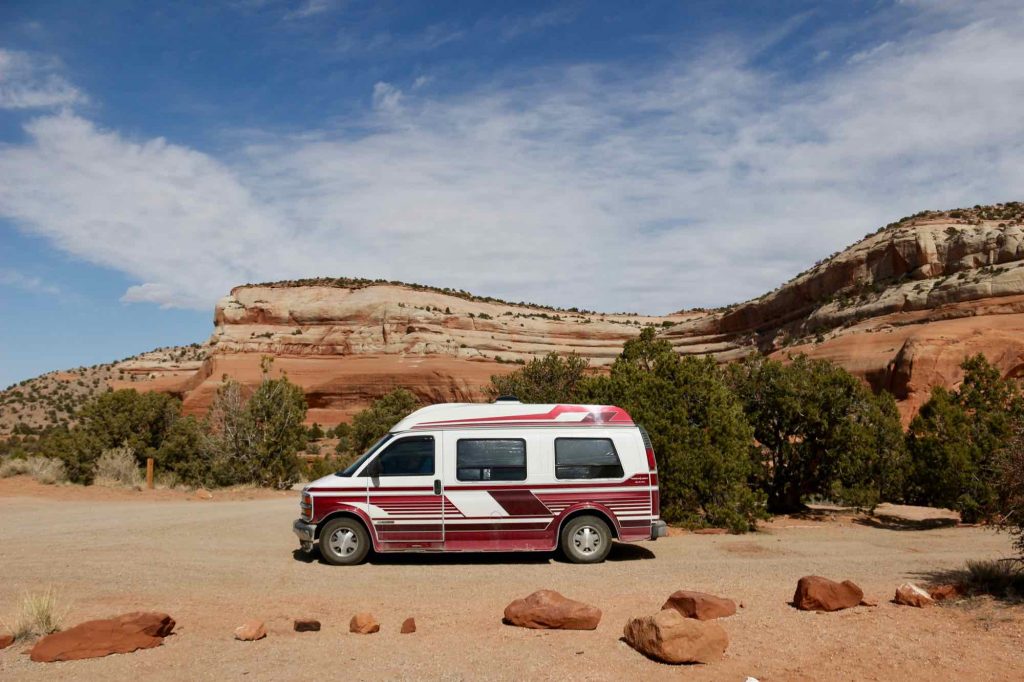 The homemade van conversion the author built, parked at a campground in front of a red rock landscape in Utah. Converting an older van is a sustainable travel choice in that it reuses something old, instead of starting from scratch. ©KettiWilhelm2021
