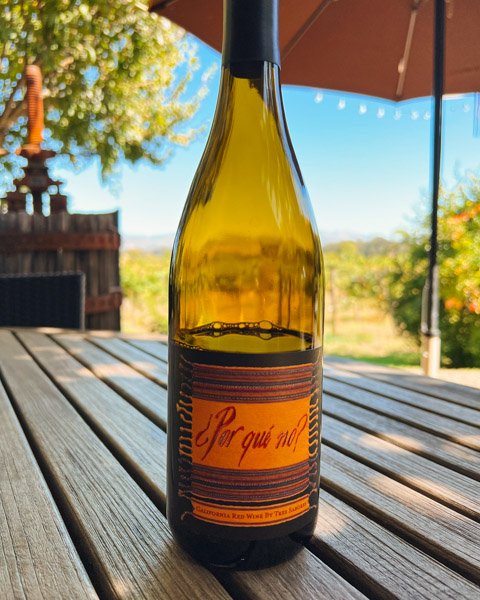 A bottle of organic wine at the Tres Sabores winery in Napa Valley, with vineyards behind it. Tres Sabores' wine club is one of my favorite ideas on this list of sustainable gift options! ©KettiWilhelm2022