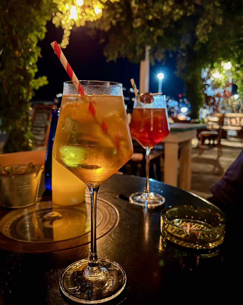 An orange cocktail at Nemo Bar, the very first to join Clean Blue Paros, in the town of Parikia, with a white and red striped paper straw sticking out of it. ©KettiWilhelm2021