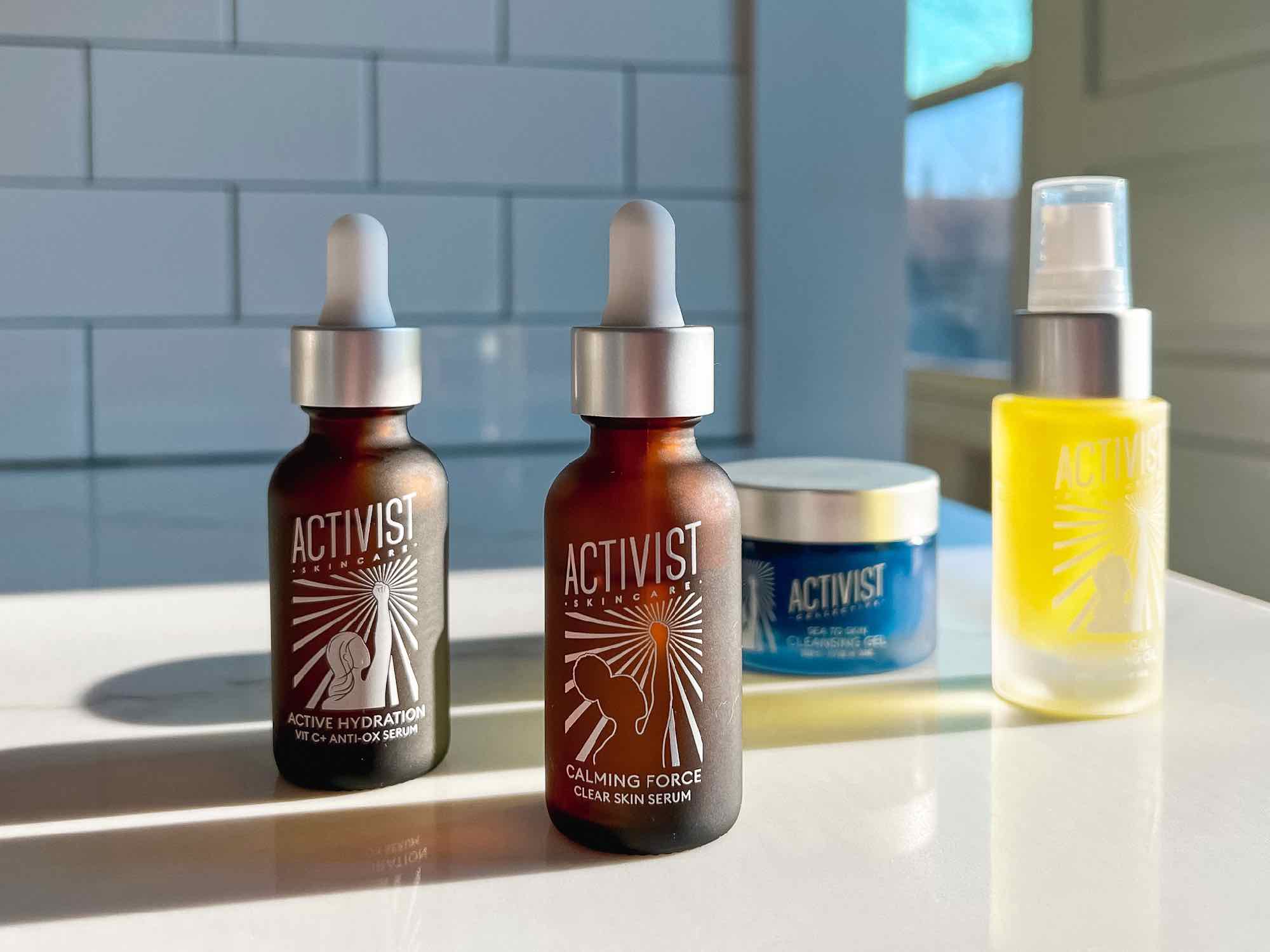 Highlights of my zero-waste skincare routine from Activist Skincare: two refillable serums, and two refillable cleansing oils, all on a clean white marble counter top with a white tile background. ©KettiWilhelm2022