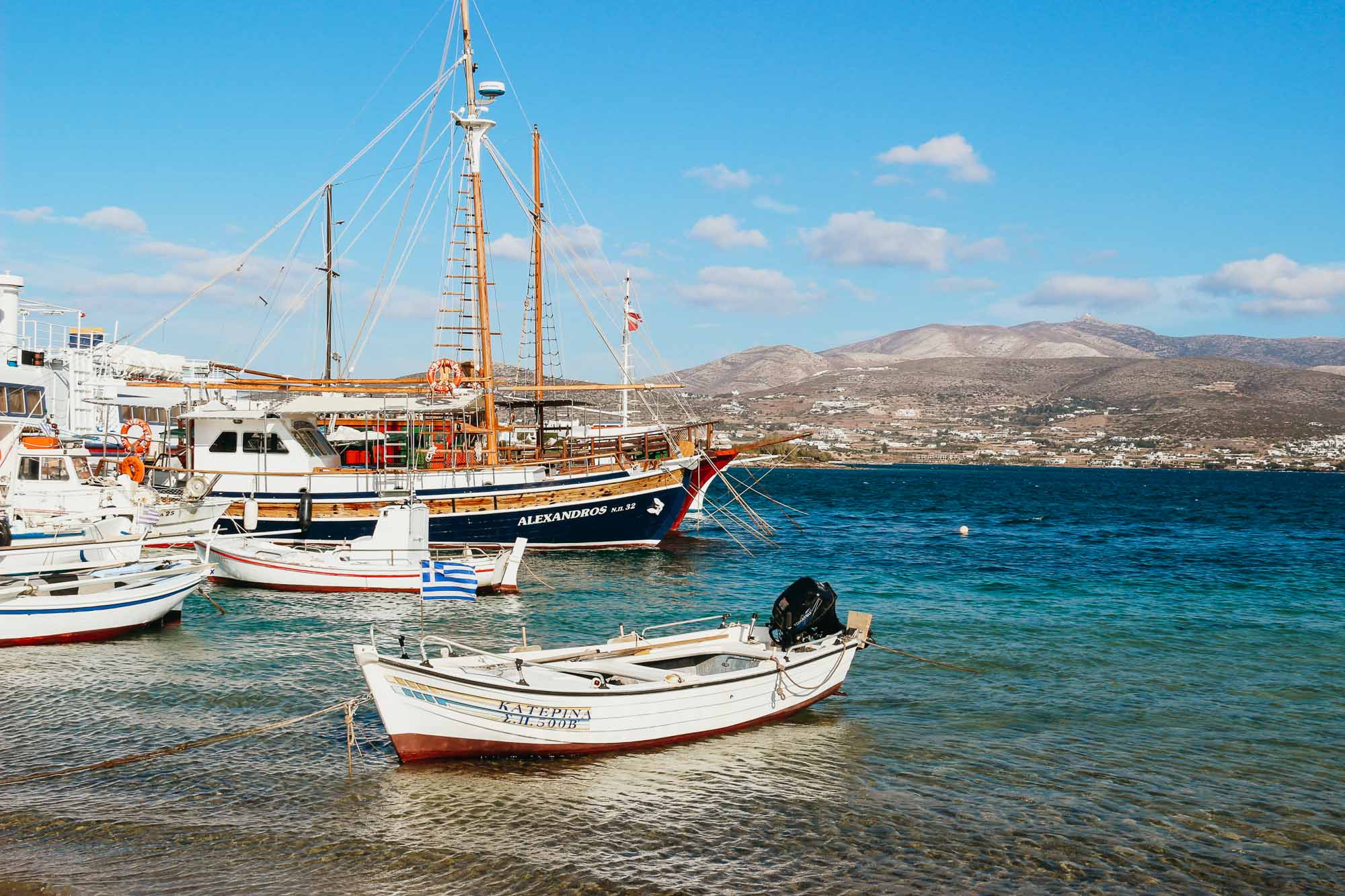 Sailboats docked in calm, turquoise, Mediterranean water on Antiparos, with the nearby island of Paros just in the background. ©KettiWilhelm2022