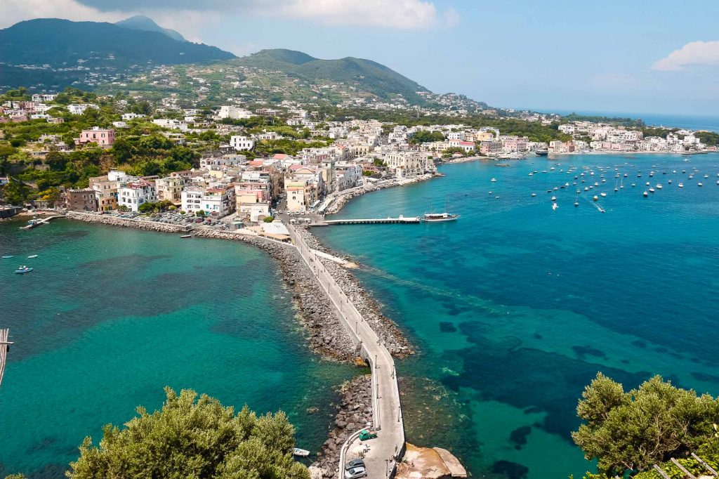 A view of the Italian island of Ischia from the Castello Aragonese d'Ischia, with turquoise waters on either side of the road leading to the castle. ©KettiWilhelm2022