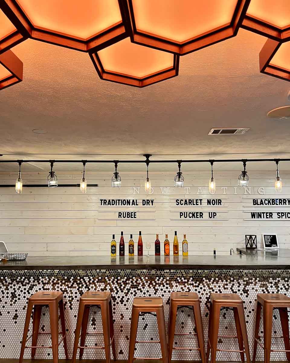 The bar at the locally-owned Queen’s Reward Meadery in Tupelo, Mississippi, with a white tile background and a honeycomb lighting feature on ceiling. ©KettiWilhelm2022