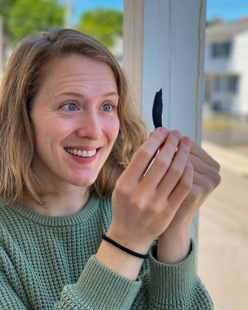 The review author holding up a toothpick-sized sliver of a black, charcoal face wash bar from Earth Harbor. ©KettiWilhelm2022