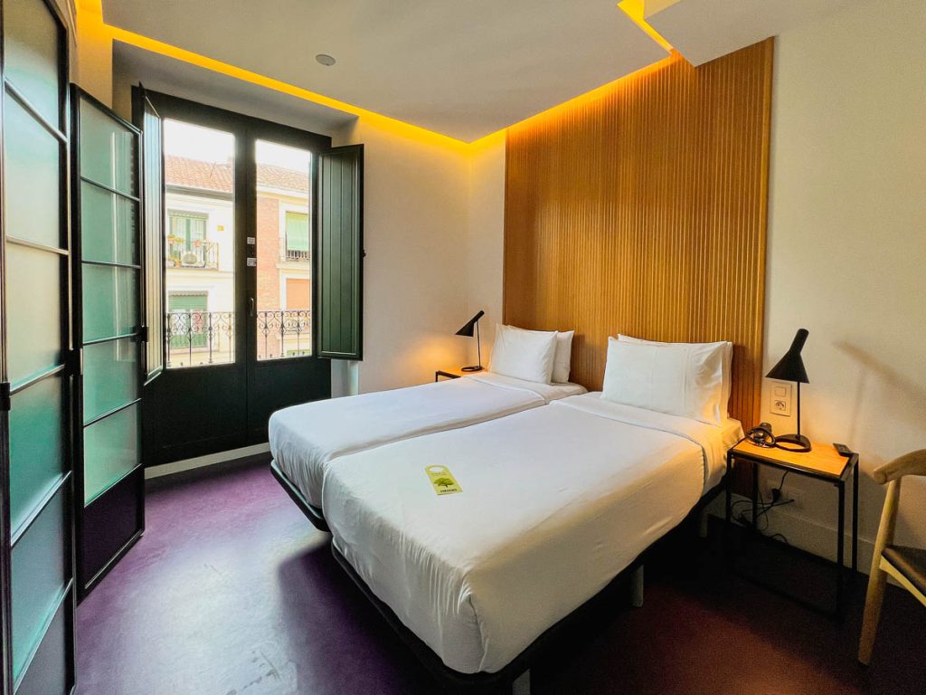 A pair of single beds with crisp white sheets in a hotel room at the Sleep'N Atocha, a sustainable hotel in Madrid, Spain. ©KettiWilhelm2023