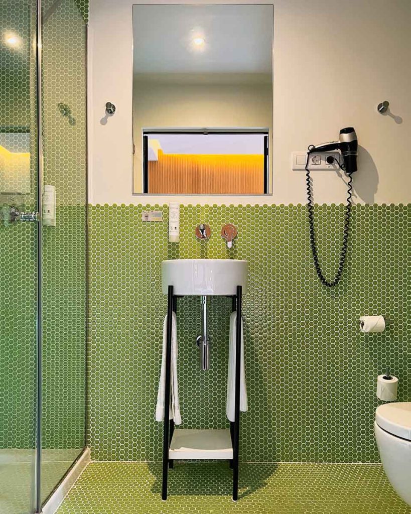 A hotel bathroom covered in bright green tiles at the Sleep'N Atocha, a sustainable hotel in Madrid, Spain. ©KettiWilhelm2023