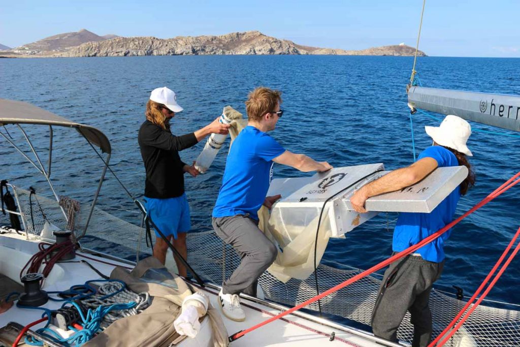 Two researchers on a sailboat, removing a trawler from the water after collecting a water sample. ©KettiWilhelm2022