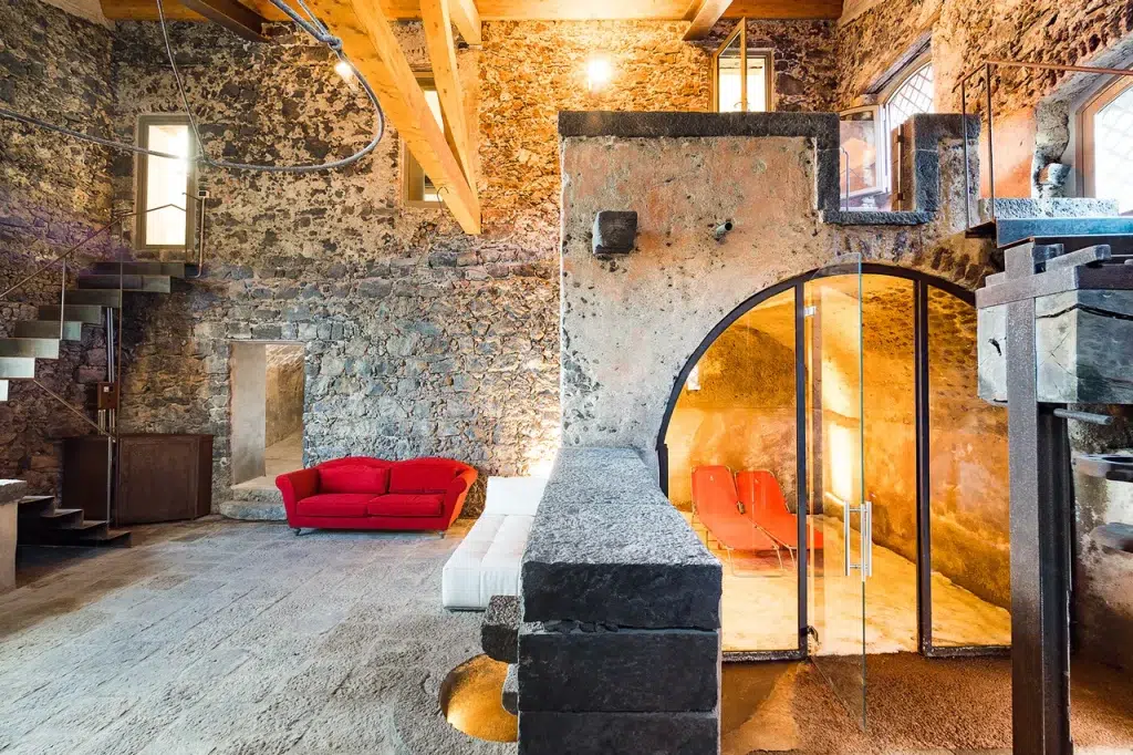 Inside the traditional stone sauna, in the walk-out basement of this villa. The walls of both the villa and spa are made of stone, and there are red couches outside the sauna.