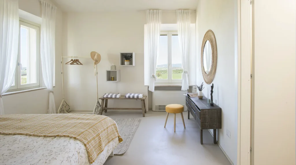 The bedroom of this villa in Tuscany, with a window looking out toward the green farm fields. 