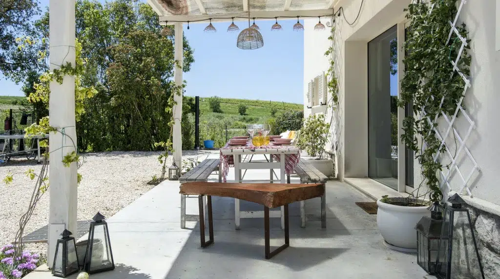 The backyard table of the sustainable Tuscan farm-stay villa for rent on Plum Guide, complete with an overhead trellis and rolling green hills. 