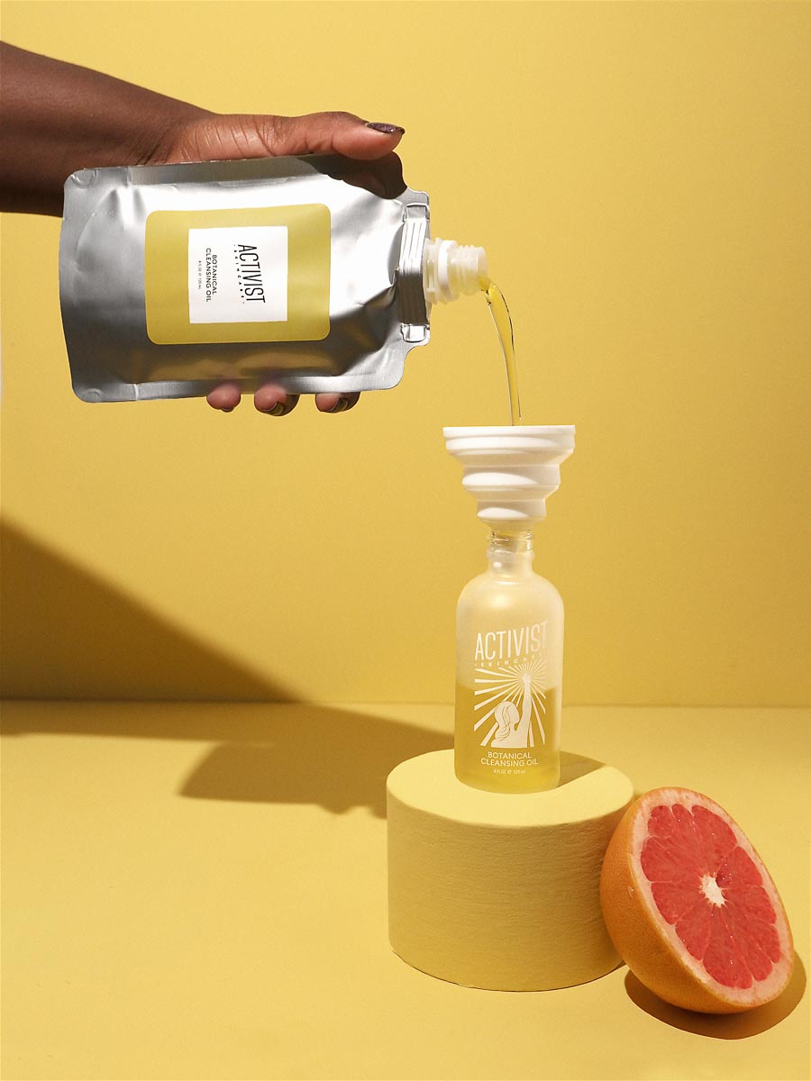 Activist Skincare's refillable packaging – a person's hand is pouring a refill into a reusable glass bottle.