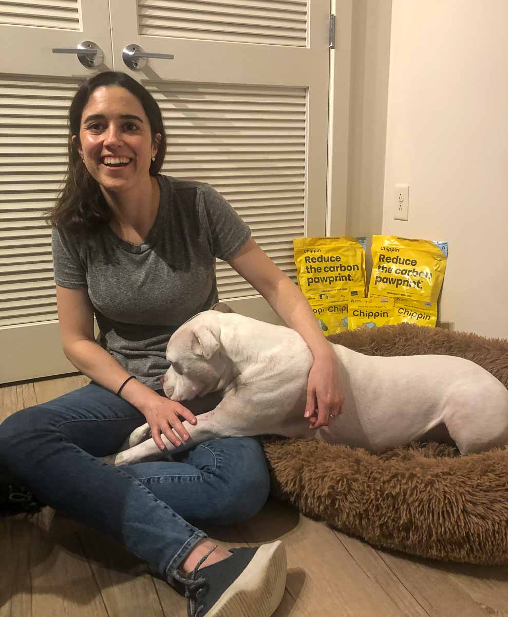 Haley, founder of the small, sustainable dog food company Chippin, sits on the floor with her dog. 