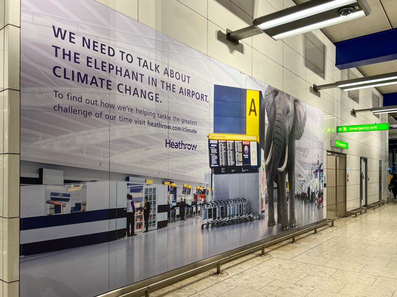A large sign at London's Heathrow airport reads: "We need to talk about the elephant in the airport: Climate change." ©KettiWilhelm2022