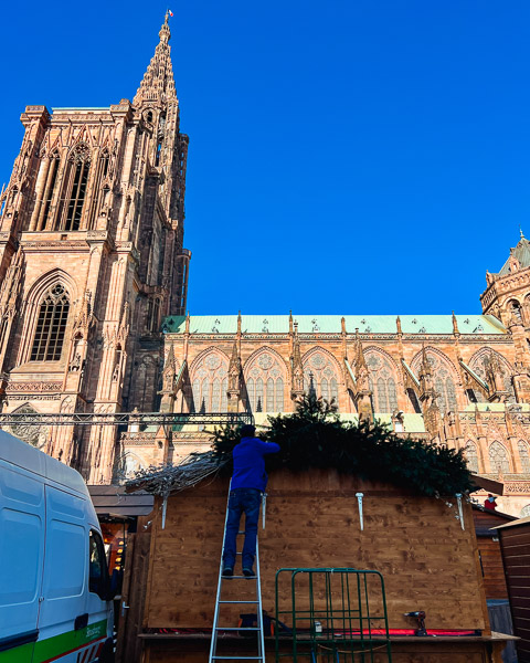 A worker installs a Christmas market stand in front of the Strasbourg Cathedral, just around the corner from where the author was hit by a delivery van. ©KettiWilhelm2023
