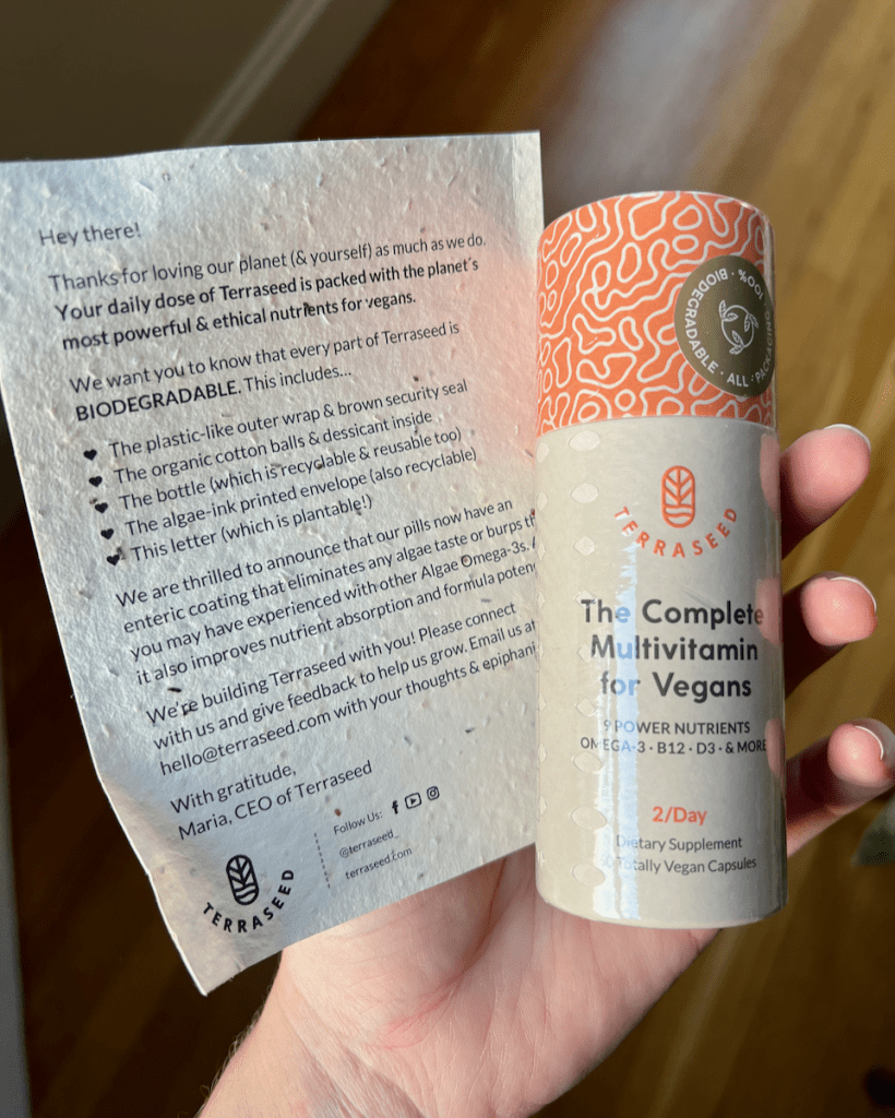A cardboard bottle of Terraseed, along with a plantable marketing insert, in the hand of the review writer. ©KettiWilhelm2023