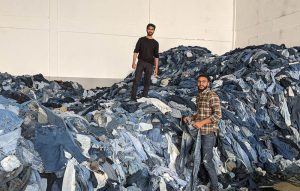 Workers stand on a pile of denim to be recycled into DL1961's circular jeans.
