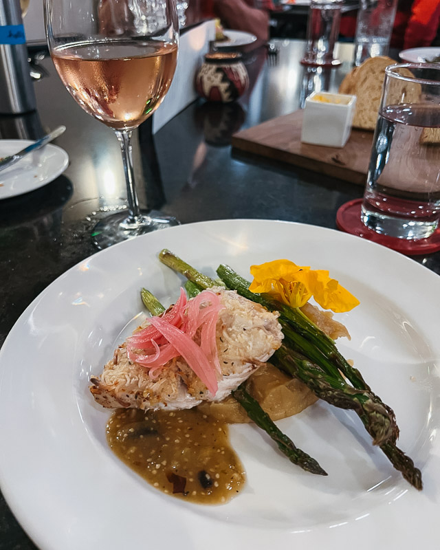 An example of the food on UnCruise in Baja: a plate of local fish with a coconut crust, fresh, organic vegetables from a local family farm, a glass of wine and freshly baked bread. ©KettiWilhelm2023