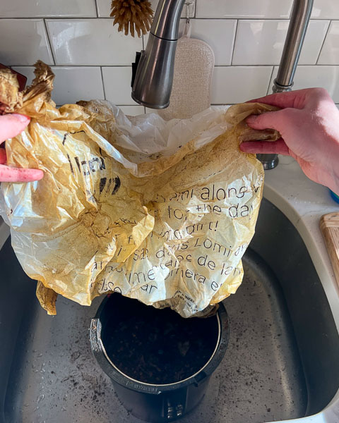 Pulling the Lomi's compostable bioplastic bag out of the Lomi composter machine after running it for the first time – it's still entirely intact and shaped like a bag, just dirty. ©KettiWilhelm2023