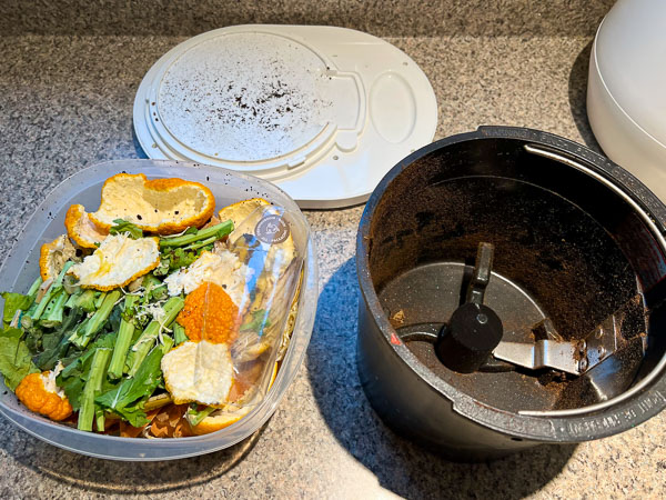 A container of food scraps and plastics (compostable bioplastic film) next to the Lomi composter bucket. ©KettiWilhelm2023