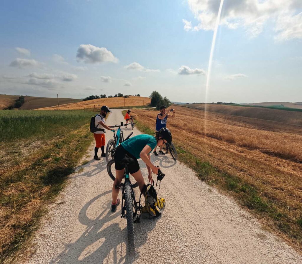 Pulling my camera out of my backpack, while the guide and other tour group members take photos on their phones during, all still standing over our electric bikes as we ride through rural Italy. ©KettiWilhelm2023