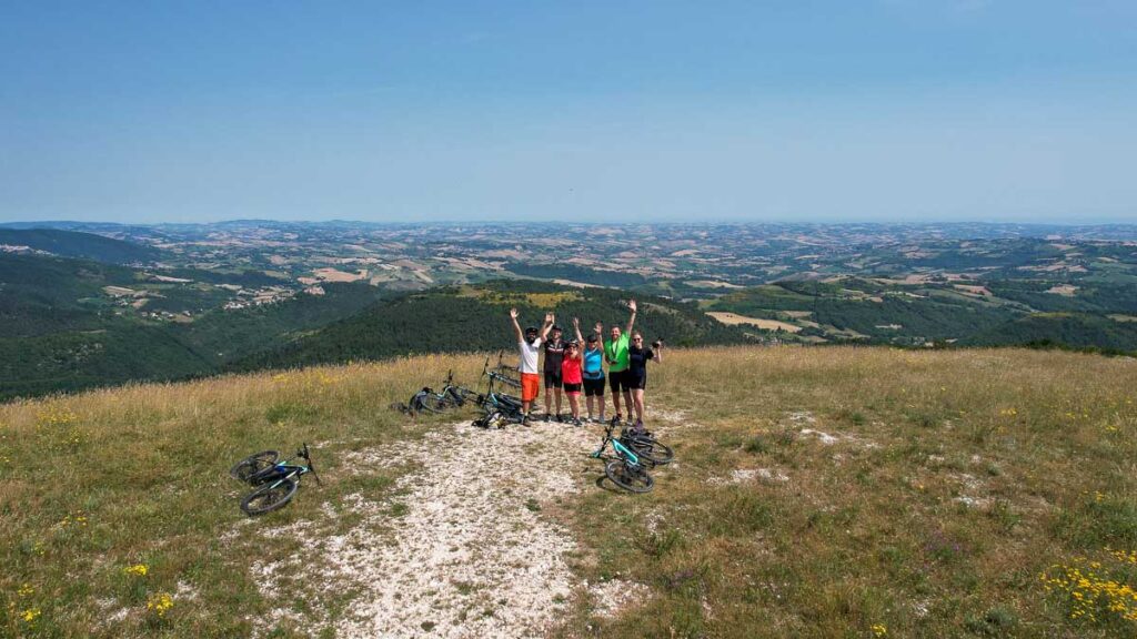 Our group of 6 on our e-bike tour in Italy's Marche region, waving at a drone for this photo from a viewpoint. ©KettiWilhelm2023