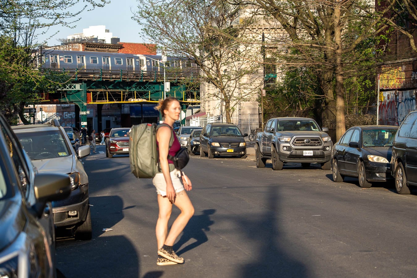 Travel blogger walking across a street in New York City wearing a travel backpack carrying everything she's packing for weeks of travel packing light in Europe. ©KettiWilhelm2026