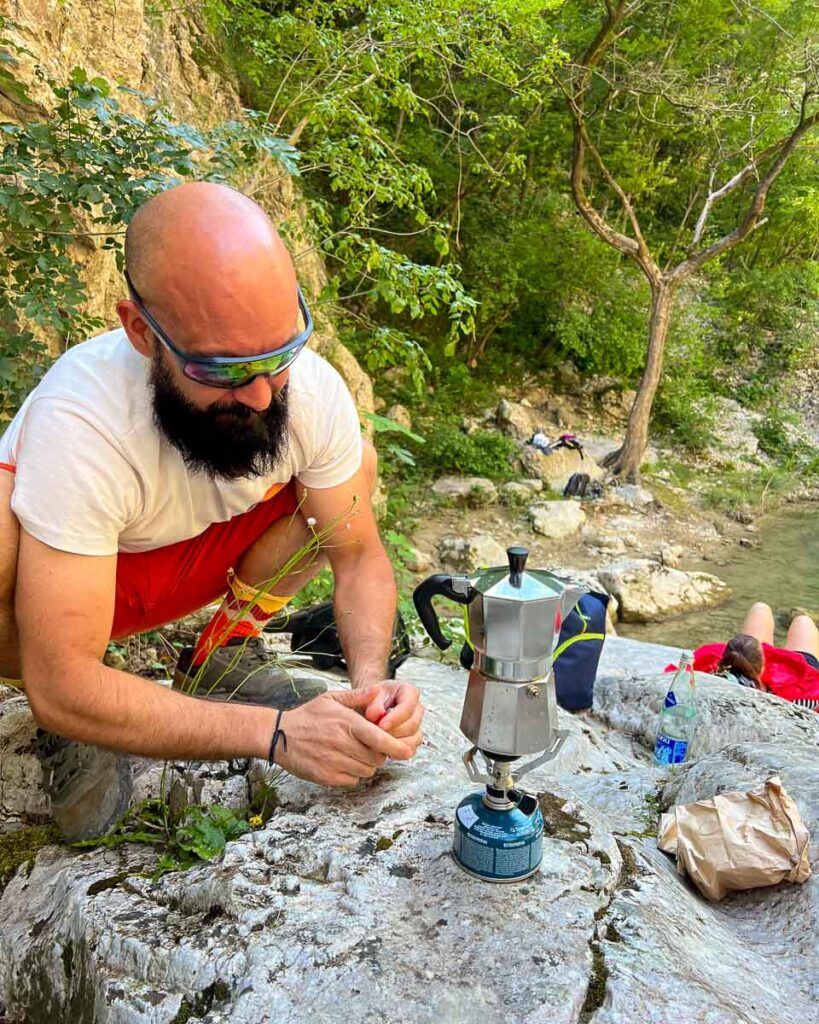 Our local bike trip guide, Marco from Basecamp523, prepares coffee in a moka pot by the side of the river where we ate our first lunch during this Marche by bike tour. ©KettiWilhelm2023