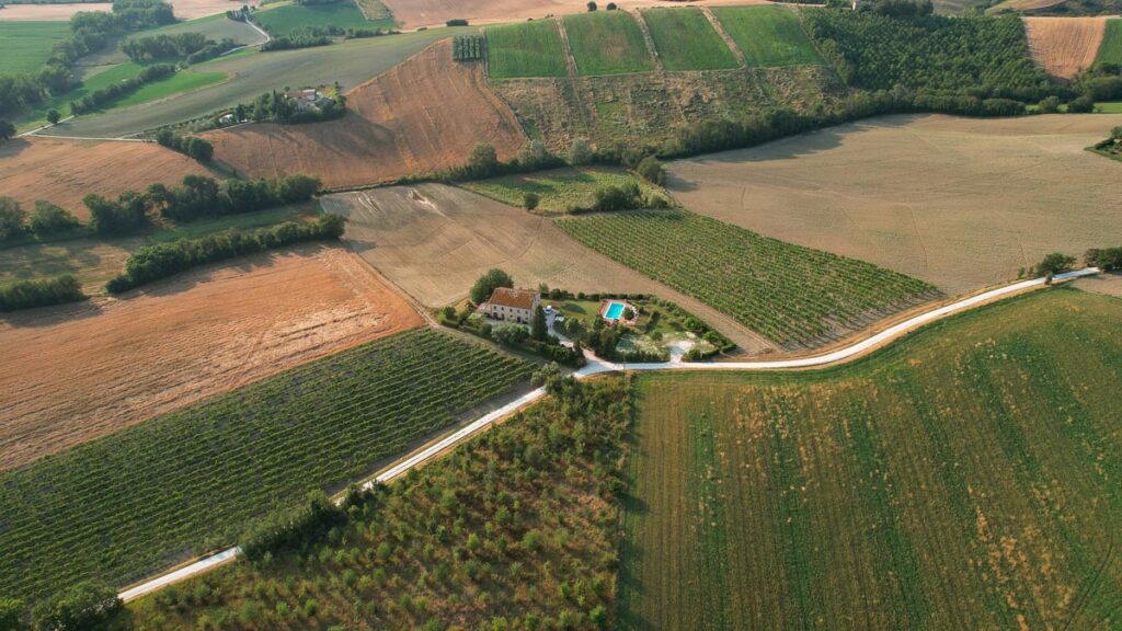 An aerial photo of an agriturismo and its pool where we stayed during this e-bike tour of Italy in the Marche region, with a white road, or "strada bianca" in front of the property and farm fields all around. ©KettiWilhelm2023
