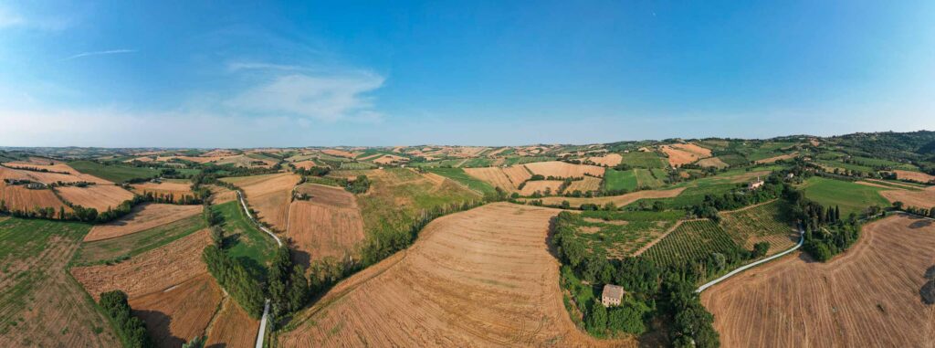 Farm fields in rural Marche, Italy, photographed from a drone showing the area of our bike tour, under bright blue June skies. ©KettiWilhelm2023