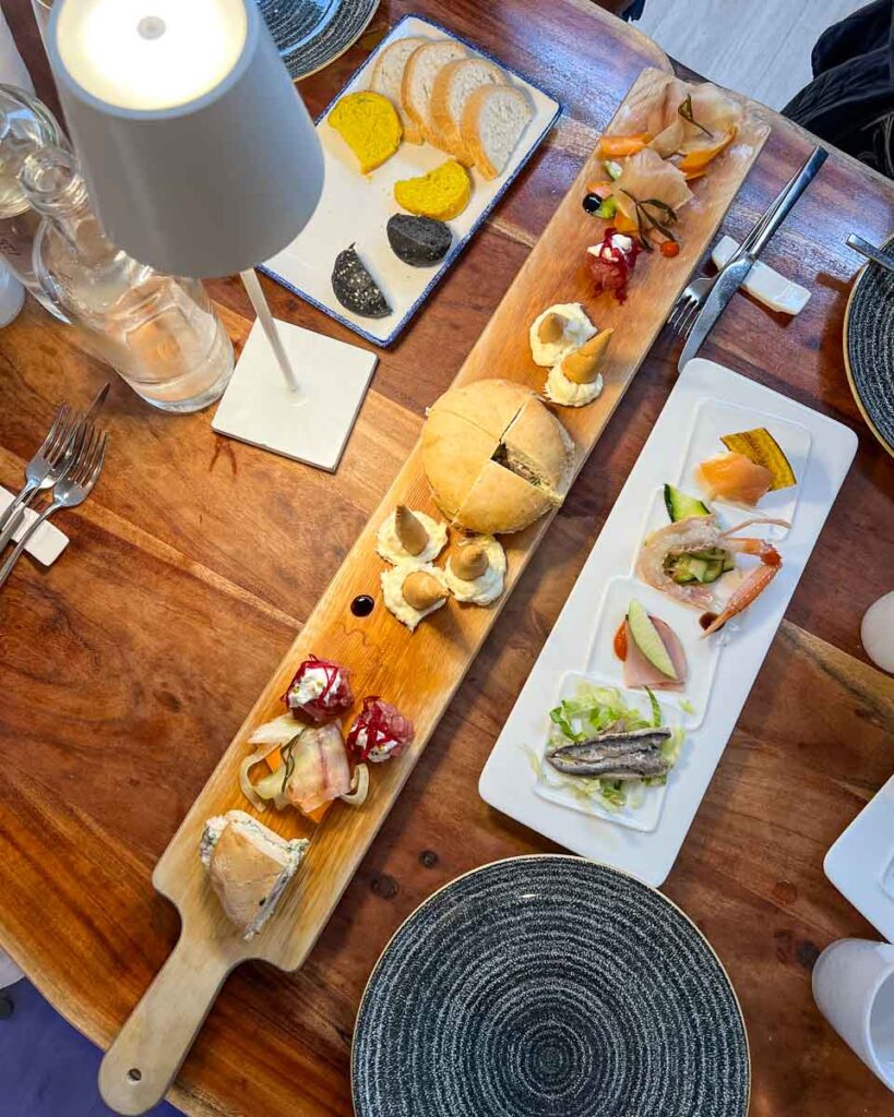 A long wooden tablet filled with local seafood appetizers at one of the best restaurants in Sirolo, Italy. ©KettiWilhelm2023