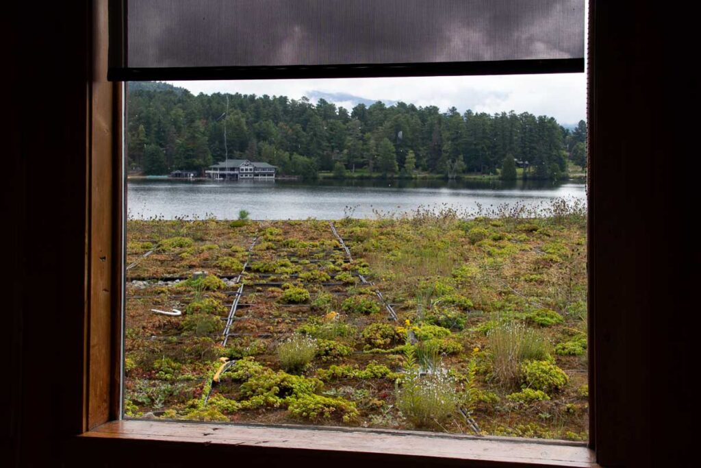 The green roof at the Golden Arrow Resort in the Adirondacks, a sustainable feature of this local hotel, seen through the window with Mirror Lake in the background. ©KettiWilhelm2023