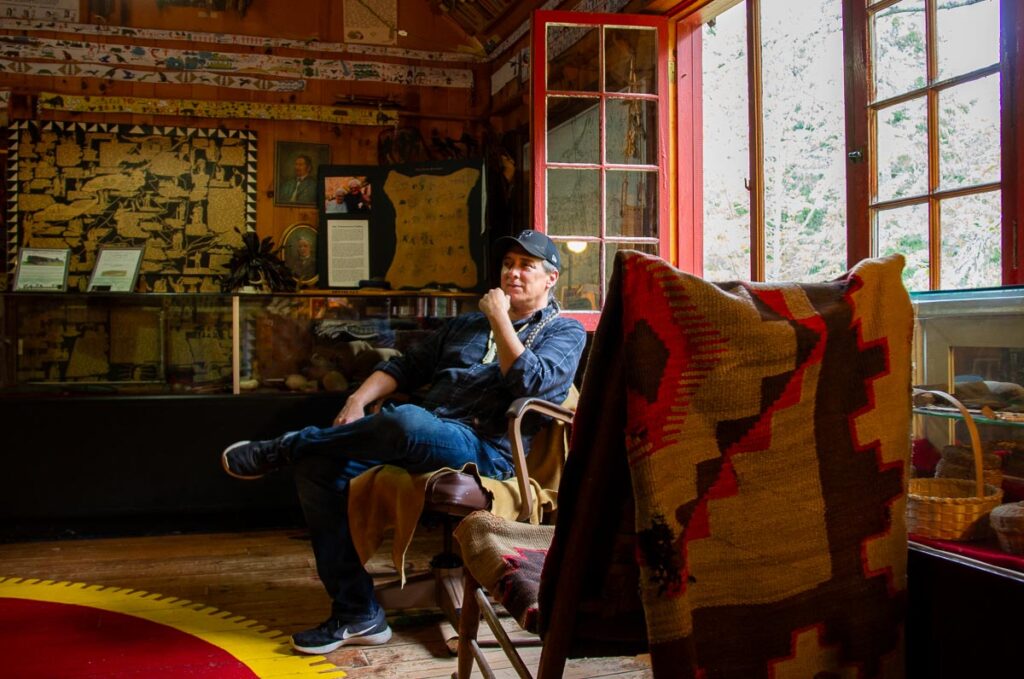 Local native artist Dave Fadden sitting in a chair by a window at his Six Nations Iroquois Cultural Center, one of the best local museums in the Adirondacks. ©KettiWilhelm2023