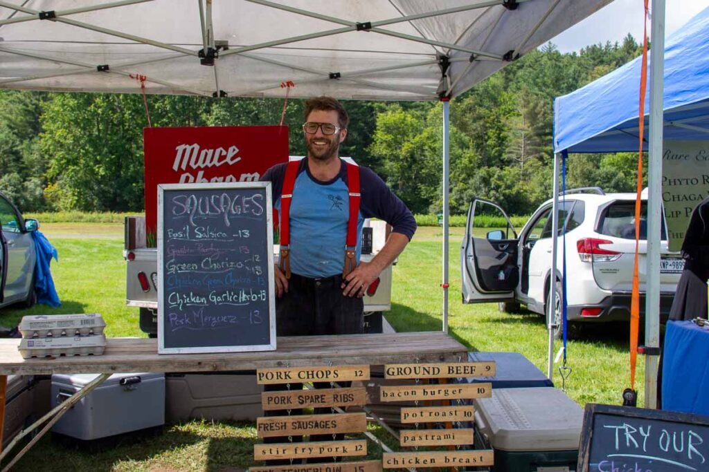 Asa from Mace Chasm Farm stands behind his booth at the Keene Valley Farmers’ Market in upstate Keene, New York. ©KettiWilhelm2023