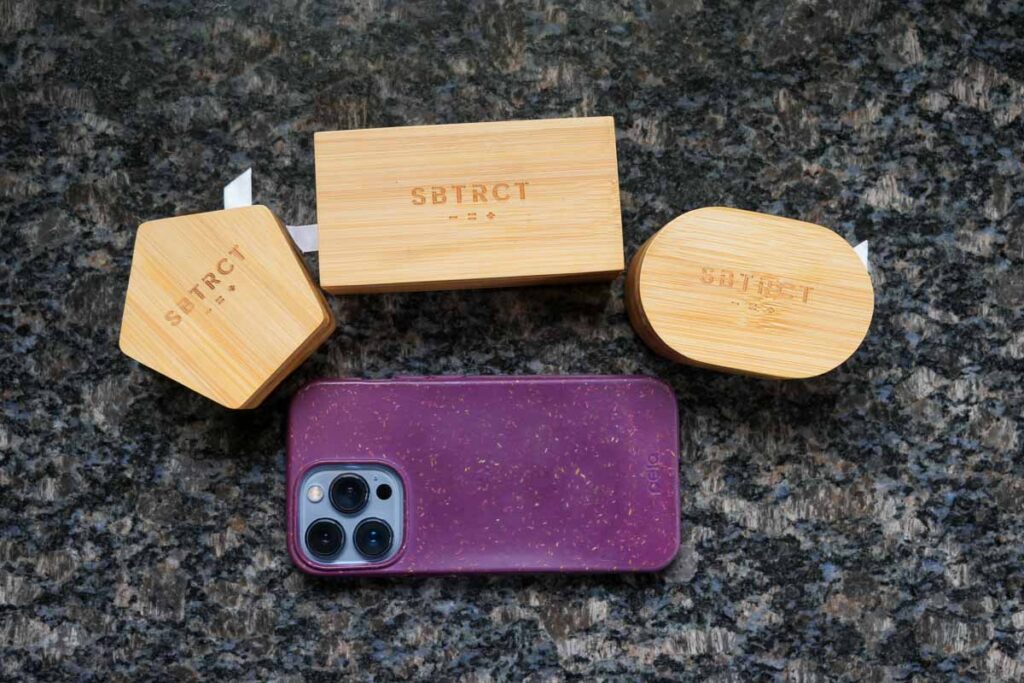 All three of my plastic-free, bamboo travel cases for SBTRCT's solid skincare line, next to an iPhone 13 Pro for scale. Each box is much smaller than the phone. ©KettiWilhelm2023