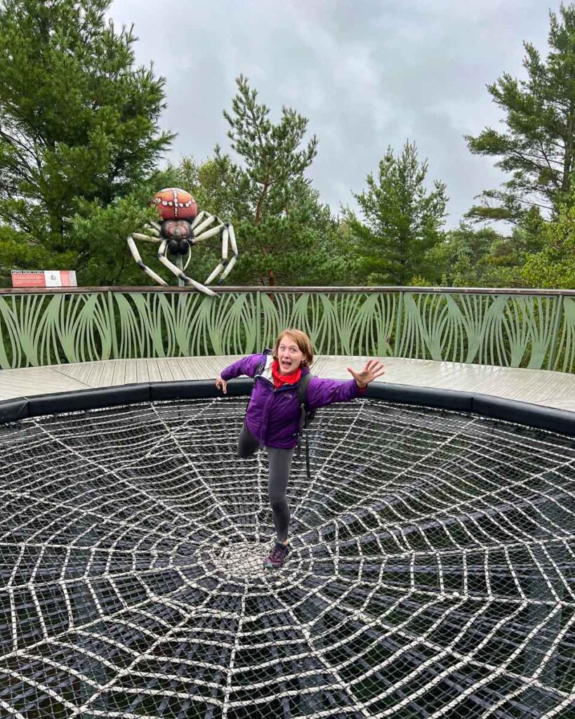 The author of this Adirondack guide pretending to be chased by a giant spider on the Wild Walk at the Wild Center. ©KettiWilhelm2023